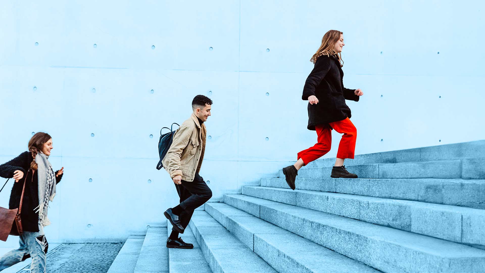 drei Personen laufen nacheinander eine große Treppe rauf